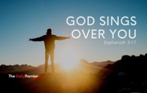 Man with hands in air - Caption reads God Sings Over You - Zephaniah 3:17