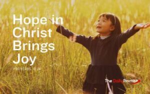 A small girl with hands raised in praise is standing in a wheat field. "Hope in Christ Brings Joy"