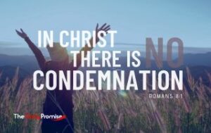 A woman standing in a field with her hands lifted in praise. - "In Christ, there is no condemnation" - Romans 8:1