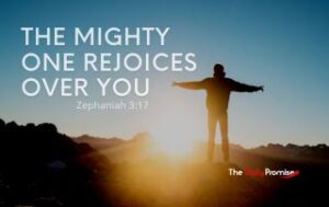 A mans standing on a hill with the sun shining on him. "The Mighty One Rejoices Over You"