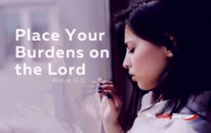 A woman is looking out a window with a worried look on her face. Beside her are the words, “Place Your Burdens on the Lord” – Psalm 55:22