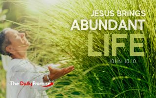 A person with their hands raises against a green background "Jesus Promises Abundant Life - John 10:10
