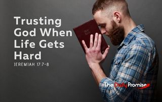 A man has his head bowed in prayer as he holds a Bible. "Trusting God When Life Gets Hard" - Jeremiah 17:7-8